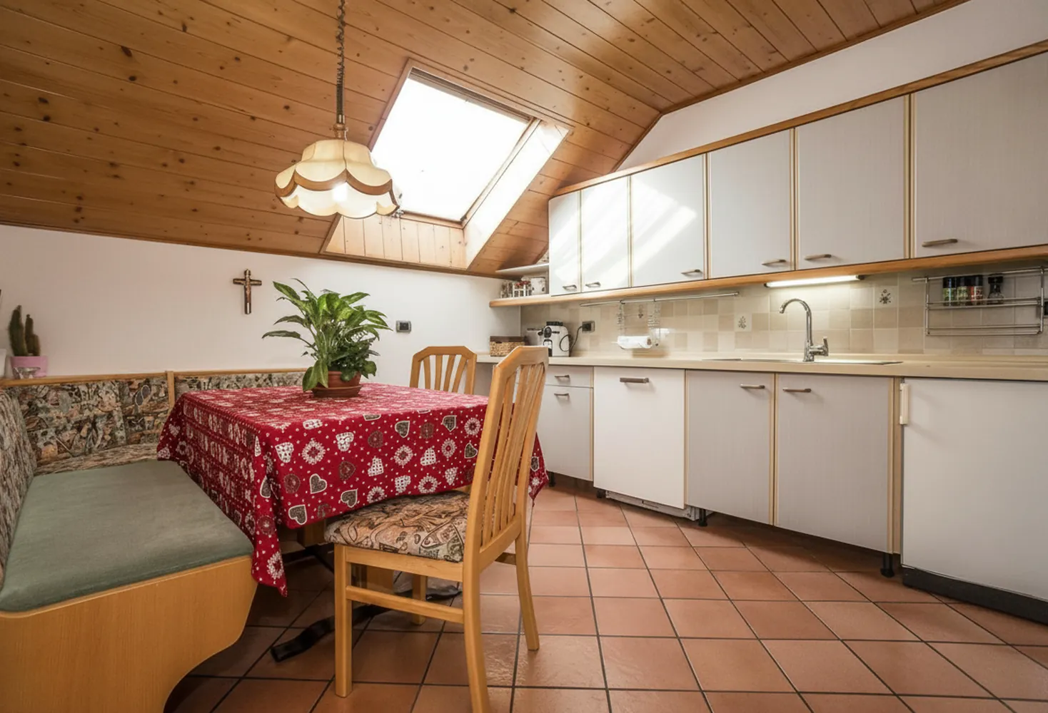 La cucina abitabile mansardata con il tavolo da pranzo, la panca e il lucernario